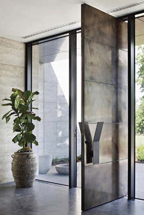 A luxury bronze pivot door open into a refined architectural space